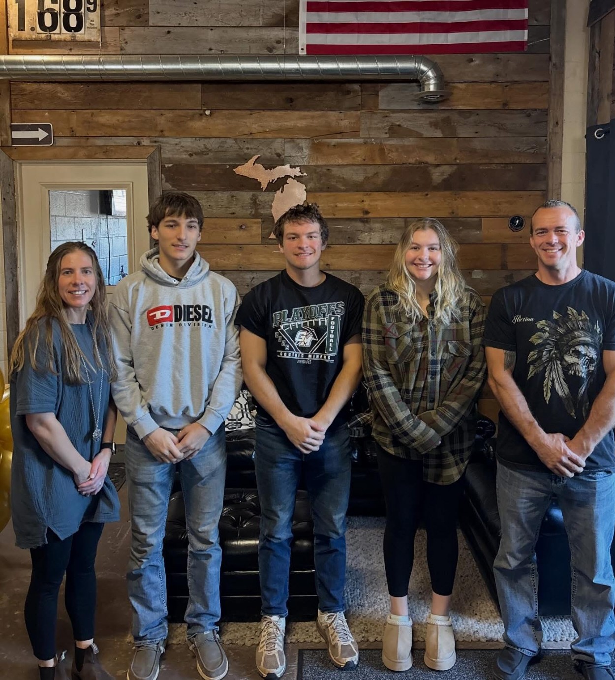 The Harju Septic crew standing together in the shop, Michigan cutout on the wall behind them