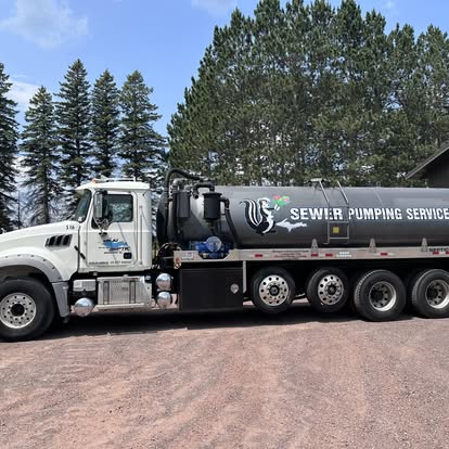 Harju Septic Service tank truck in profile with pines behind, serving Iron County Wisconsin