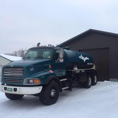 Harju tank truck outside the garage in deep snow — winter septic service in the western U.P.